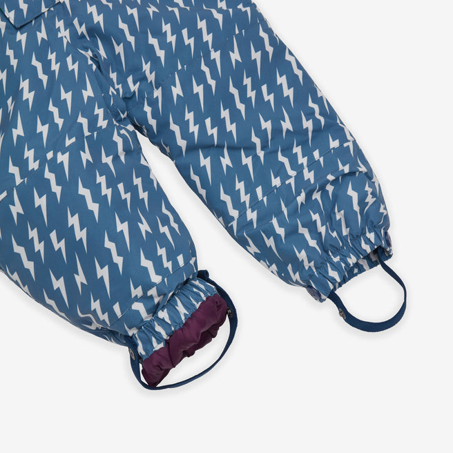 Close-up of an EcoWarm Waterproof Snowsuit Blue, legs patterned with white lightning bolts, ends with purple cuffs and blue straps.